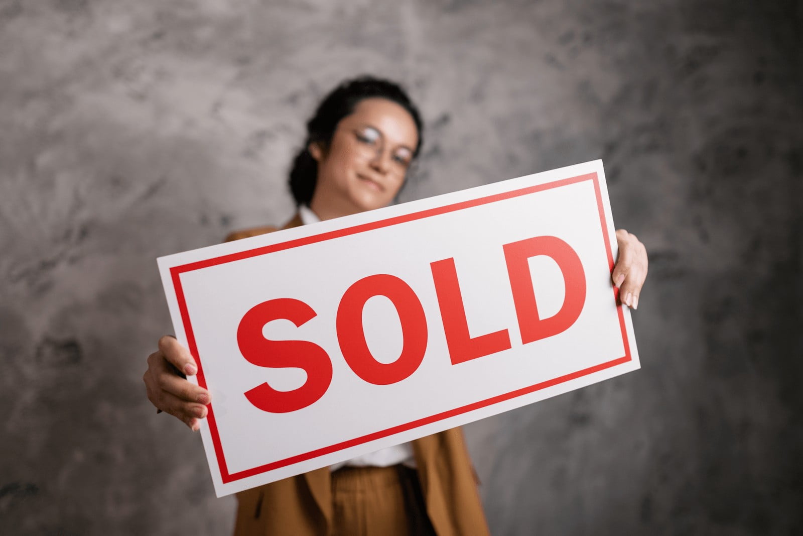 a real estate agent is holding a sold sign